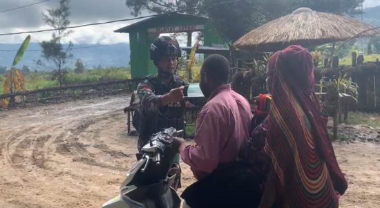 Tampak anggota TNI sedang membagikan Masker kepada warga. (Foto : Satgas Pamtas)