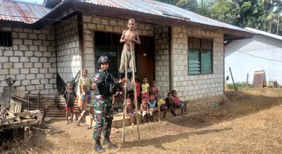 Tampak seorang anggota TNI sedang bersama anak anak Kabupaten Keerom Papua mengajarkan permainan Engrang. (Foto : Satgas Pamtas Yonif 126/KC)