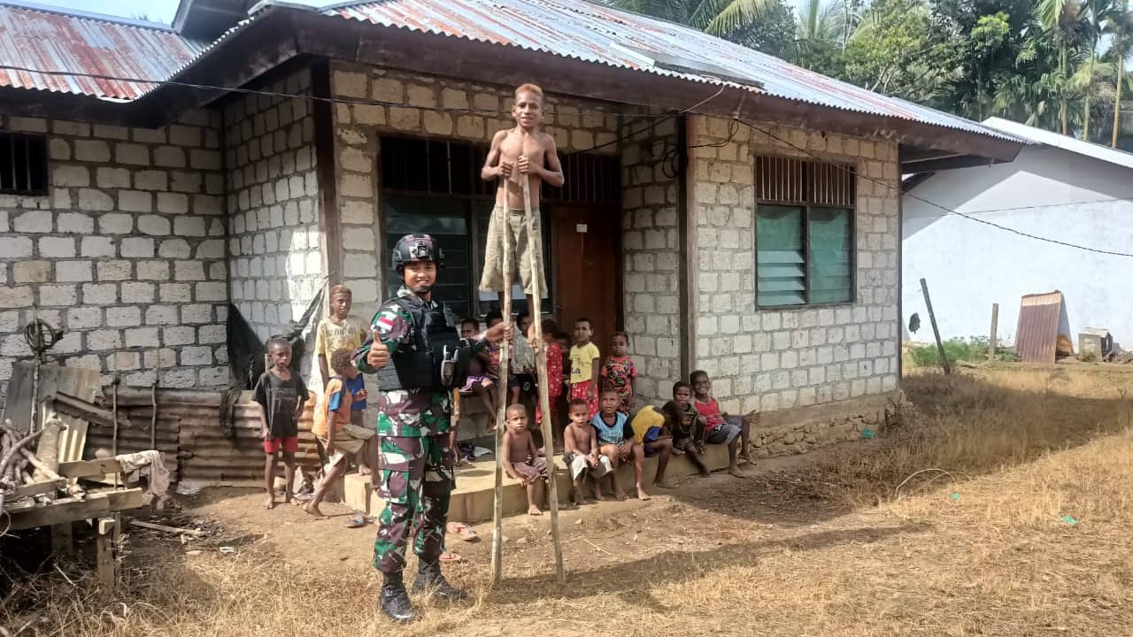 Tampak seorang anggota TNI sedang bersama anak anak Kabupaten Keerom Papua mengajarkan permainan Engrang. (Foto : Satgas Pamtas Yonif 126/KC)