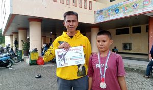 Pedrosa, Pelajar asal SDN 2 Ujanmas Baru berhasil menyabet gelar juara 2 pada kejuaraan Taekwondo Bupati Cup 2022. Tampak foto, Pedrosa bersama sang Ayah seusai menerima medali