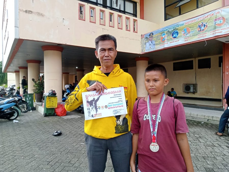 Pedrosa, Pelajar asal SDN 2 Ujanmas Baru berhasil menyabet gelar juara 2 pada kejuaraan Taekwondo Bupati Cup 2022. Tampak foto, Pedrosa bersama sang Ayah seusai menerima medali